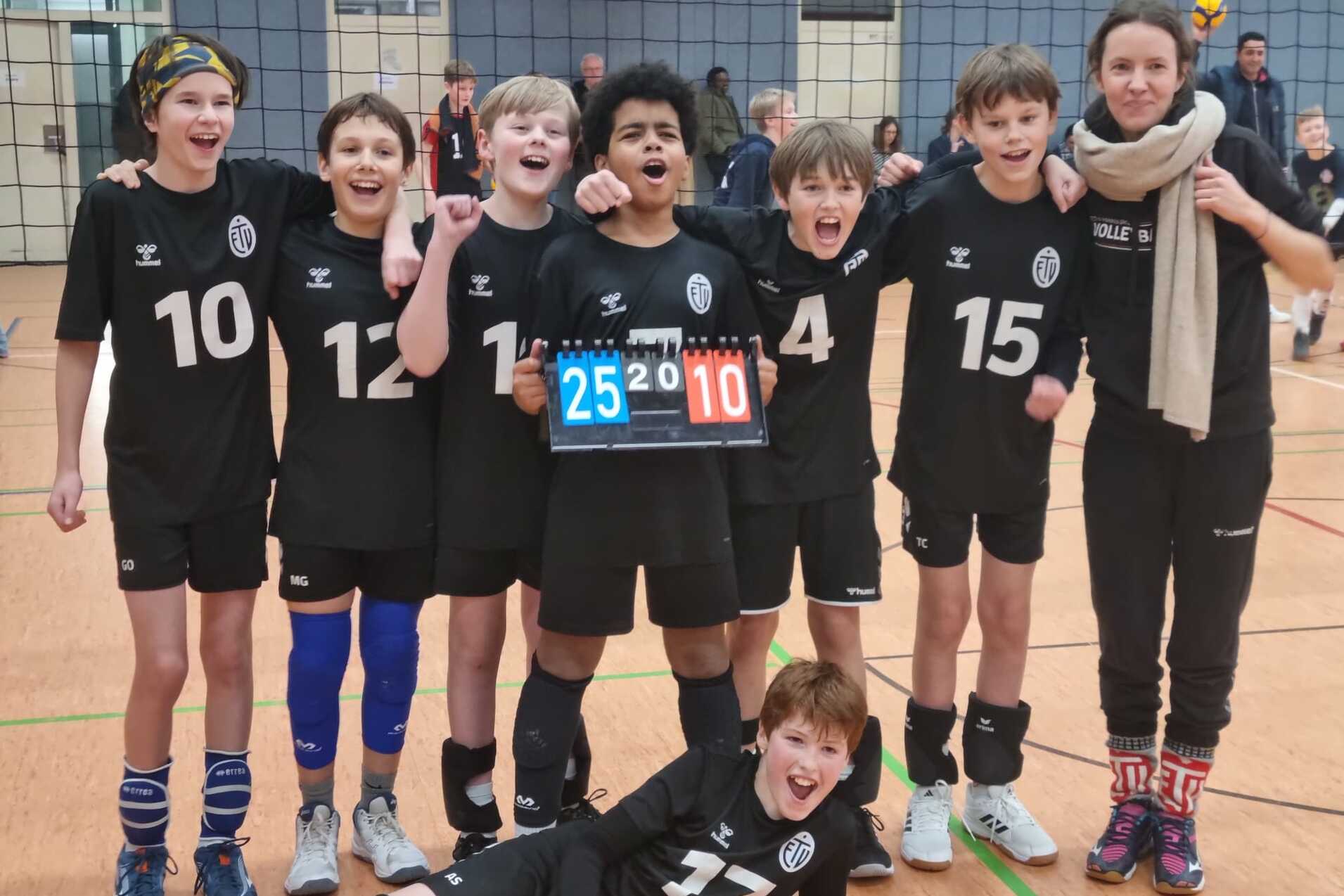 Gruppe junger Volleyballspieler jubelt nach einem Sieg, halten ein Punkteschild mit 25:10 in der Mitte.