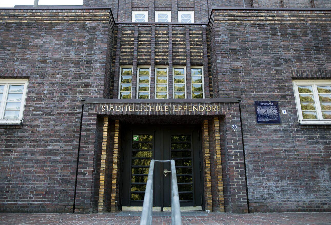 Eingang der Stadtteilschule Eppendorf mit gläsernen Türen und Mauerwerk aus roten Ziegeln.
