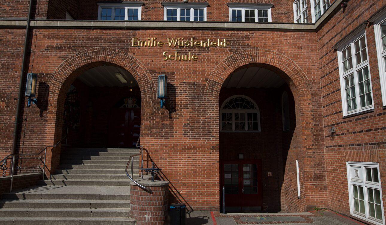 Eingang zur Emilie-Wisland-Schule mit Treppen und großen Bögen aus roten Ziegelsteinen.