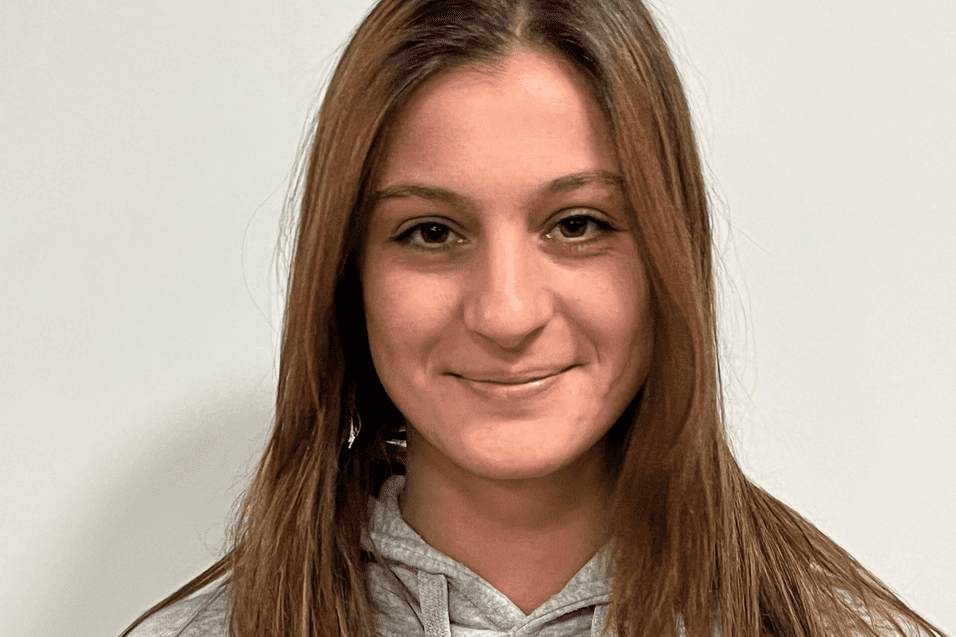 Portrait einer jungen Frau mit langen, braunen Haaren in einem grauen Hoodie mit dem Aufdruck "ETV HAMBURG BASKETBALL".