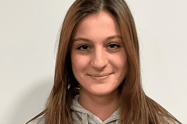 Portrait einer jungen Frau mit langen, braunen Haaren in einem grauen Hoodie mit dem Aufdruck "ETV HAMBURG BASKETBALL".