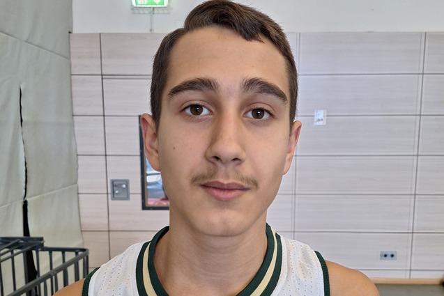 Junger Basketballspieler im Trikot mit dem Aufdruck „Bucks“ steht in einer Sporthalle vor Basketballkörben.