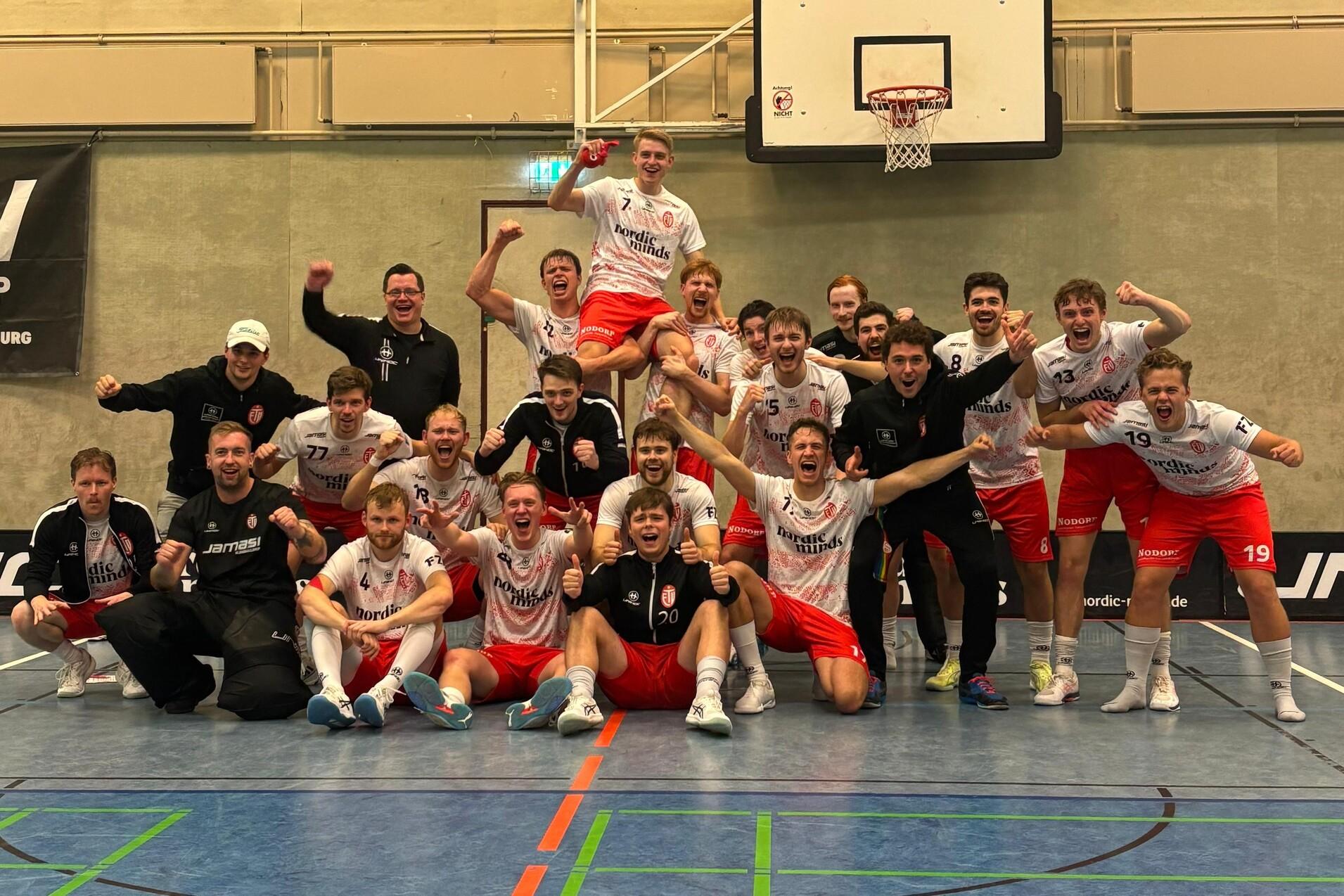 Gruppe jubelnder Spieler und Trainer auf einem Sportplatz, freuen sich über den Spielstand von 5:3 auf der Anzeigetafel.