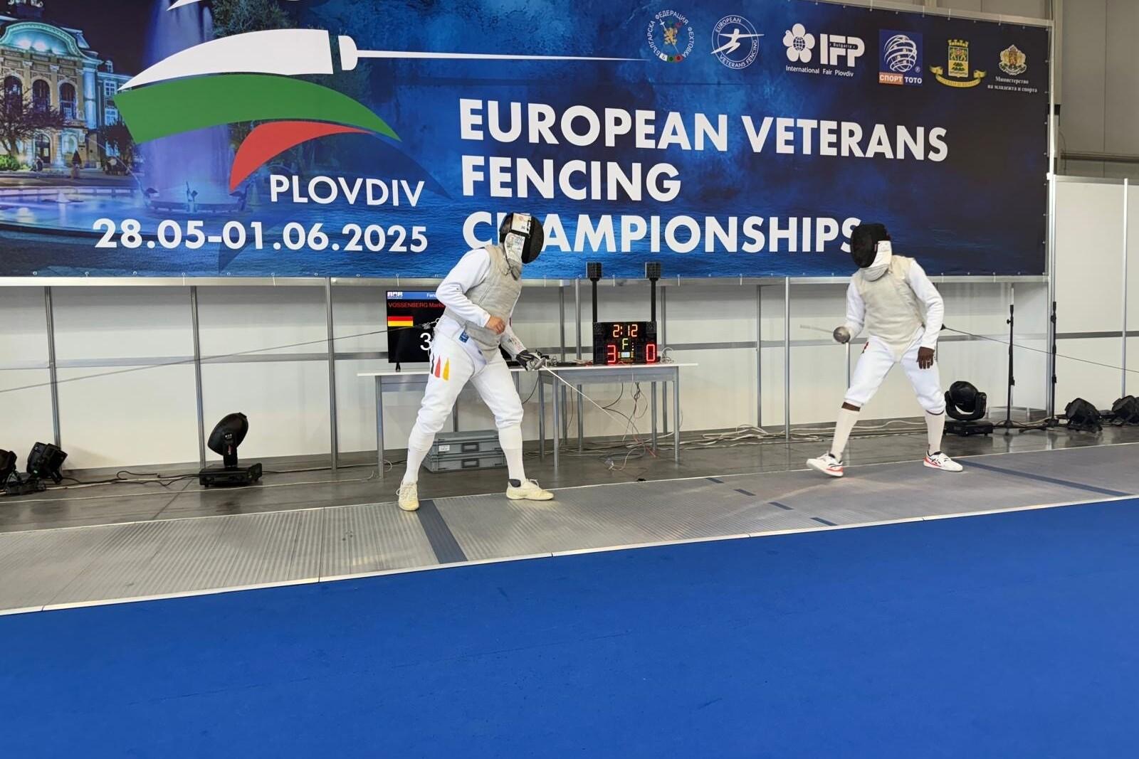 Zwei Fechter in Vollmontur kämpfen auf einer blauen Fläche während der Europäisches Veteranen-Fechtmeisterschaft in Plovdiv.