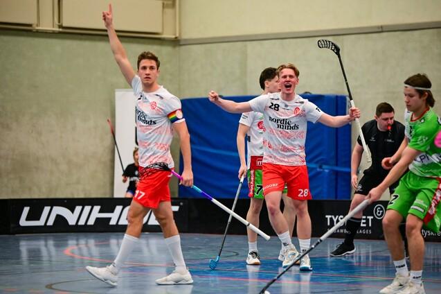 Zwei Spieler feiern einen Torerfolg im Floorball-Match, während andere Spieler auf dem Spielfeld konzentriert sind.