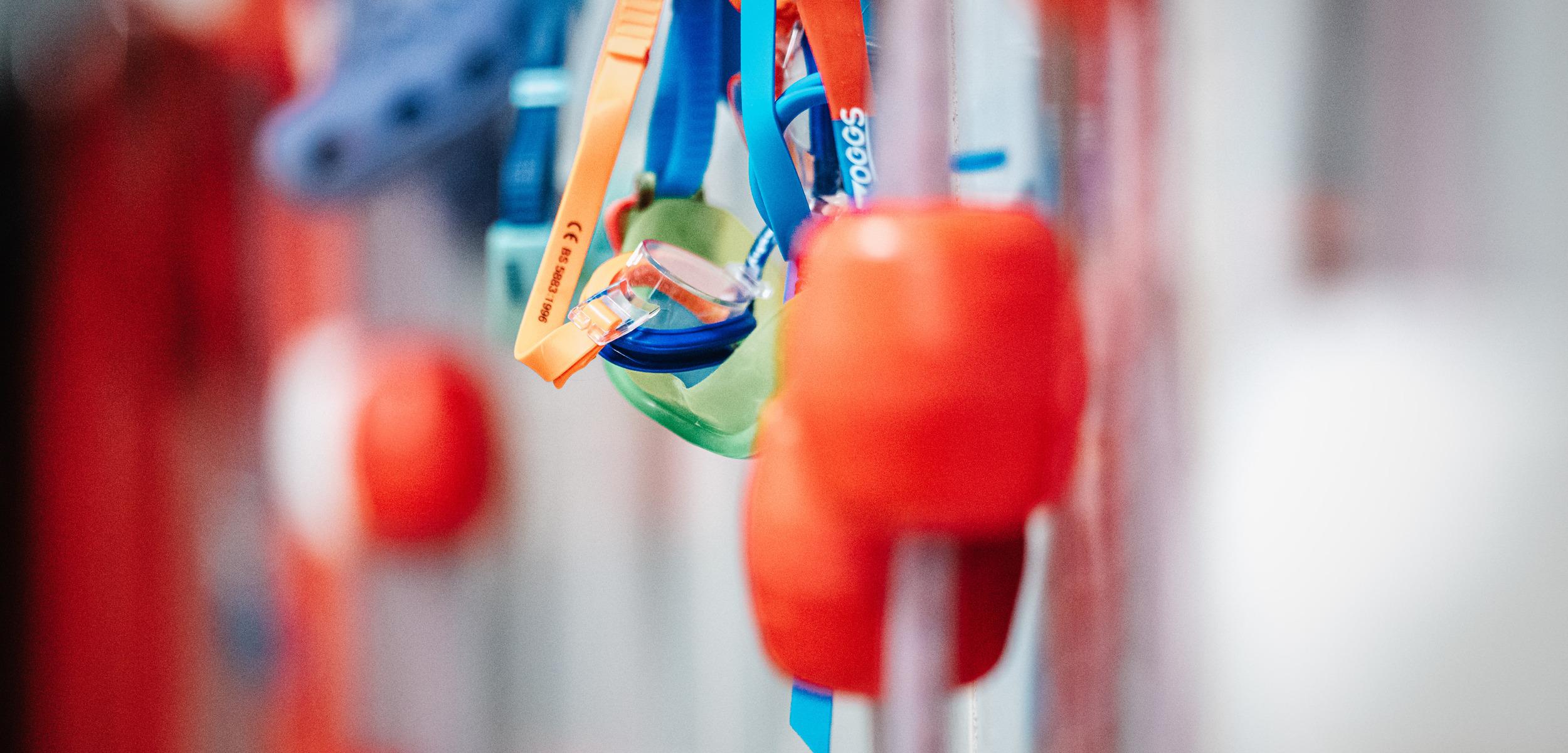 Bunte Kletterschuhe und Sicherungsgeräte hängen an einer Kletterwand in einem Indoor-Kletterpark.